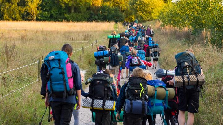 Spejderflok med rygsæk der går ud af grusvej